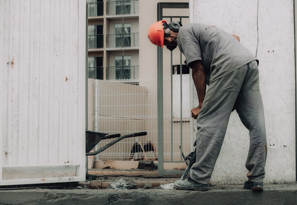 Man in hard hat operating a jackhammer on an outdoor construction site.